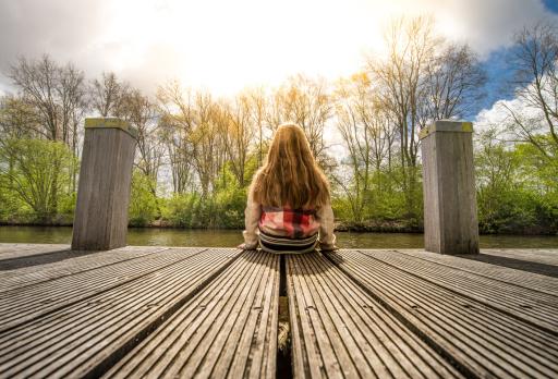 small girl sitting on a dock