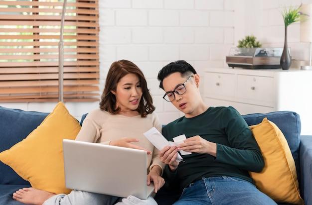 Free photo serious asian husband checking analyzing statement utilities bills sitting together at home