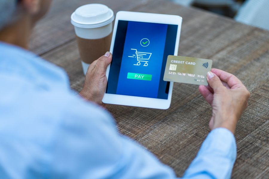 A person holding a credit card and a tablet