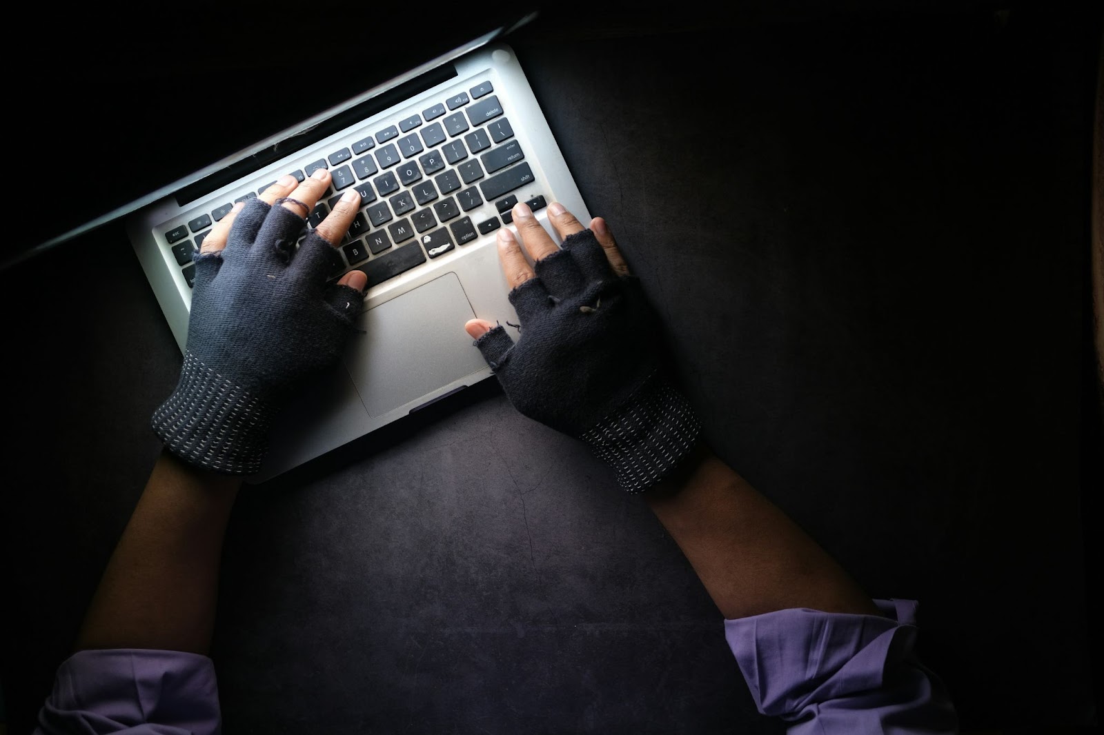 2 hands with black gloves on a notebook keyboard