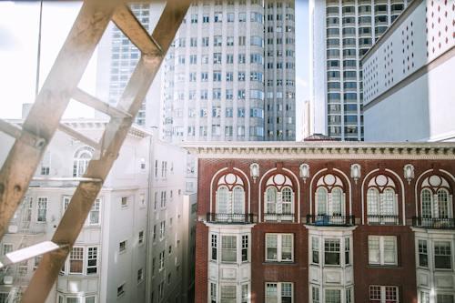 Free Facades of residential houses with small balconies and decorated windows located in modern city Stock Photo