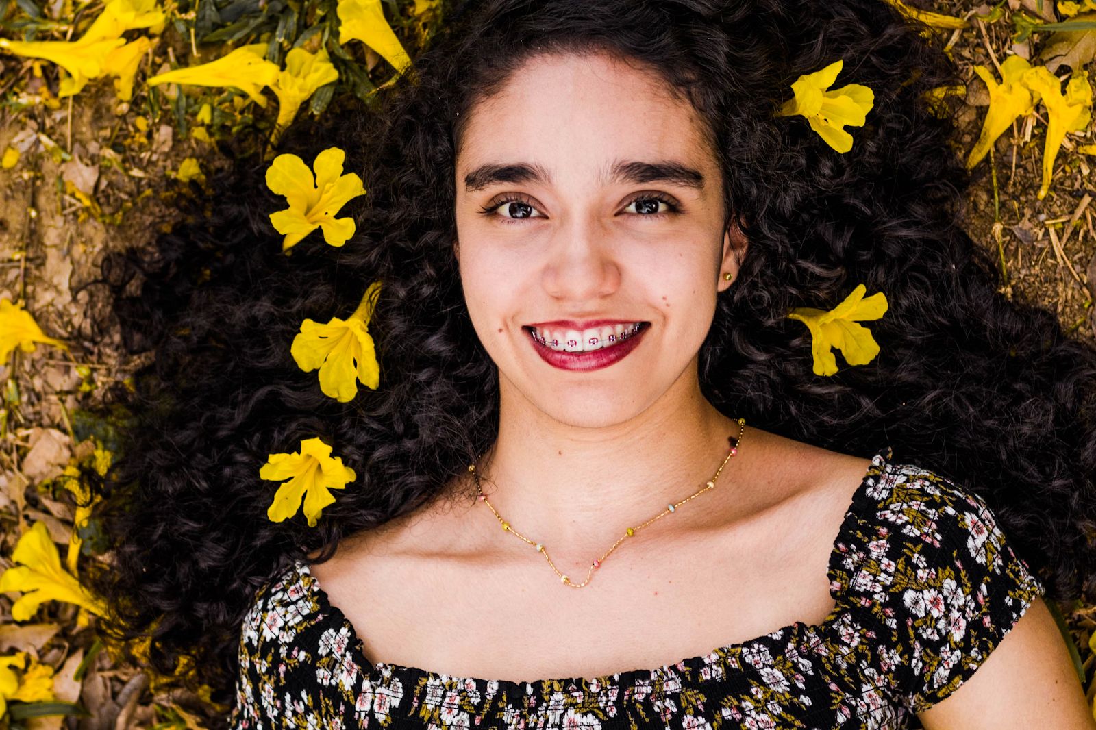 girl showing her braces while smiling and with flowers in her hair