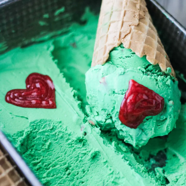 Grinch ice cream, mint chocolate with hearts in waffle cone.