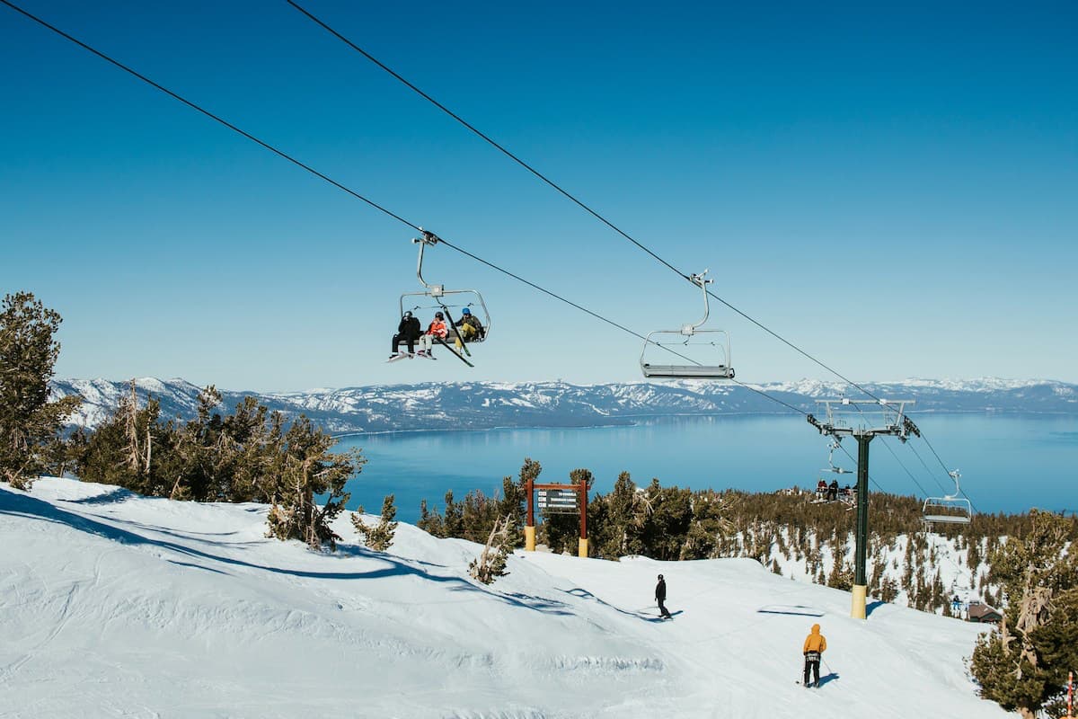 Skiiers on heavenly mountain in Lake Tahoe with chair lift in the middle and Lake Tahoe and mountain view in background