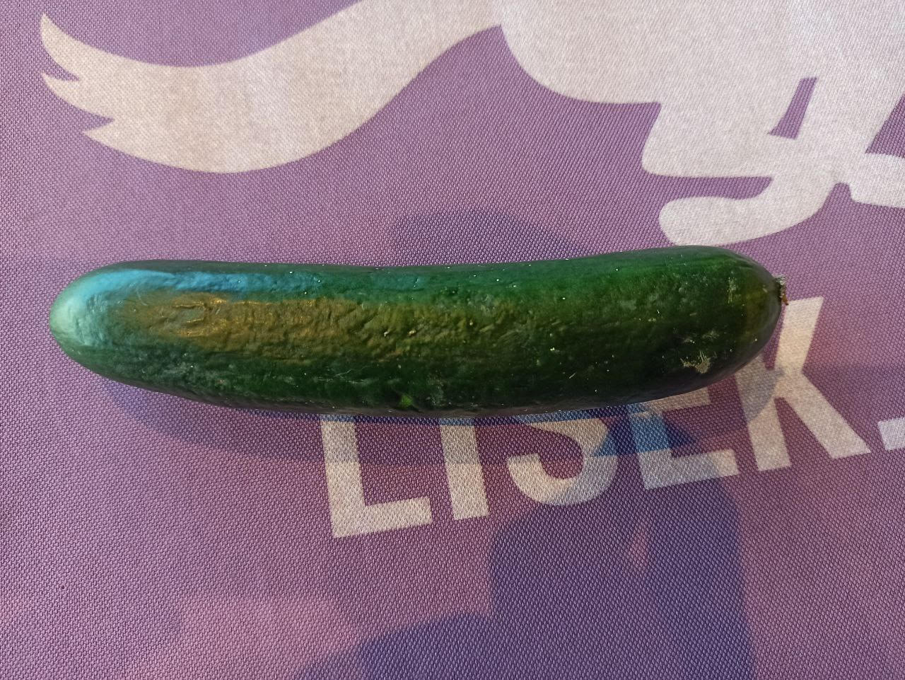 A green cucumber on a purple surface

Description automatically generated