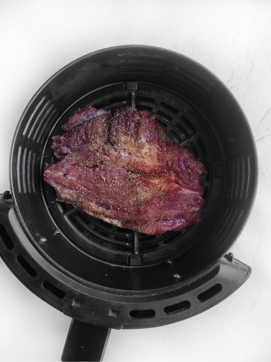 A ribeye steak is being cooked on a bbq grill.
