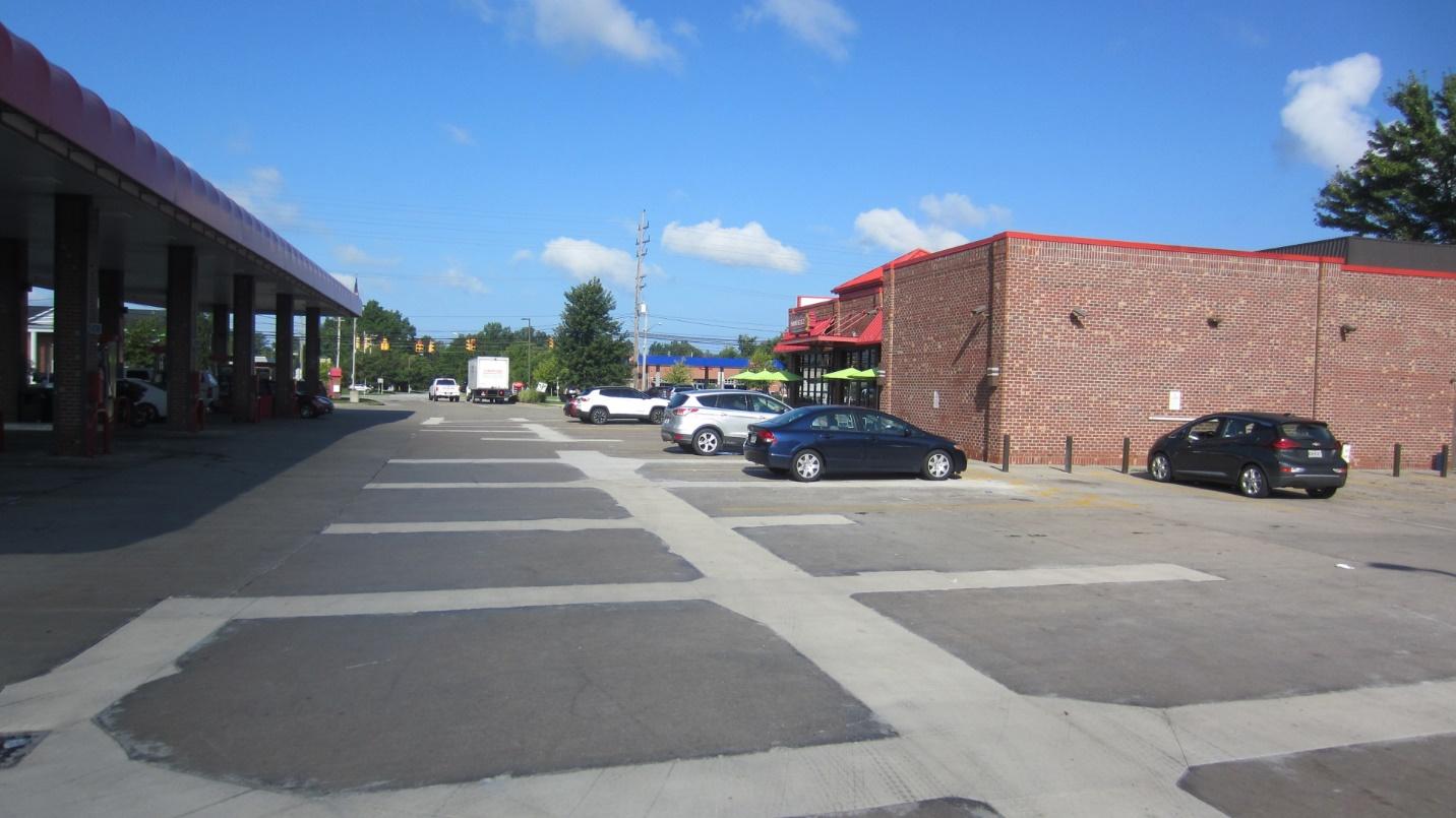 A parking lot with cars parked in front of a building

Description automatically generated