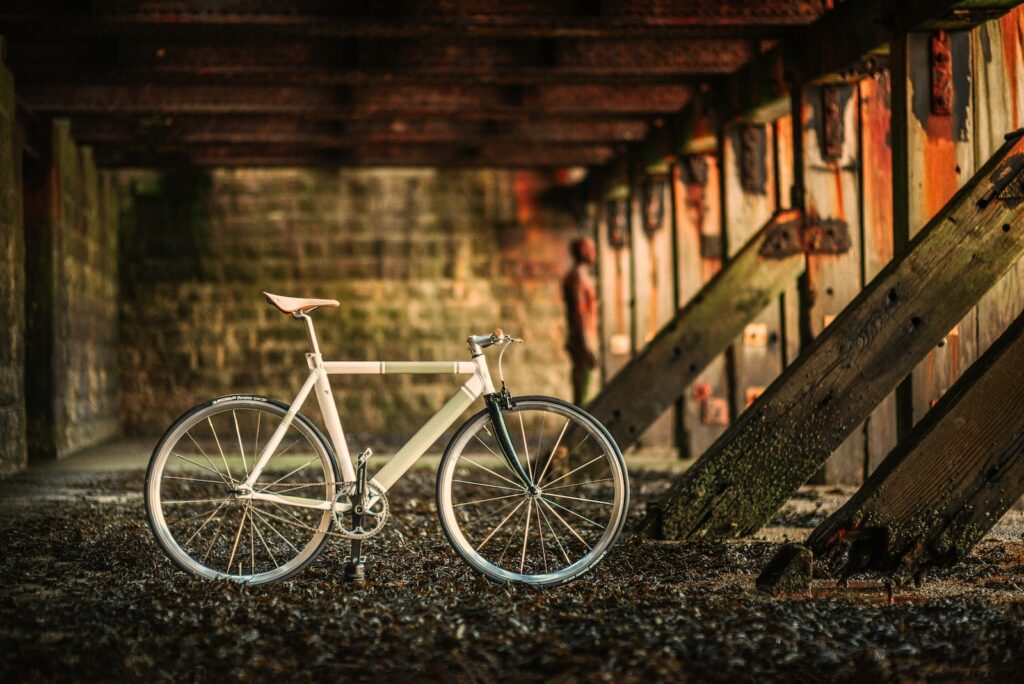 white city bike parked beside brown wooden fence during daytime