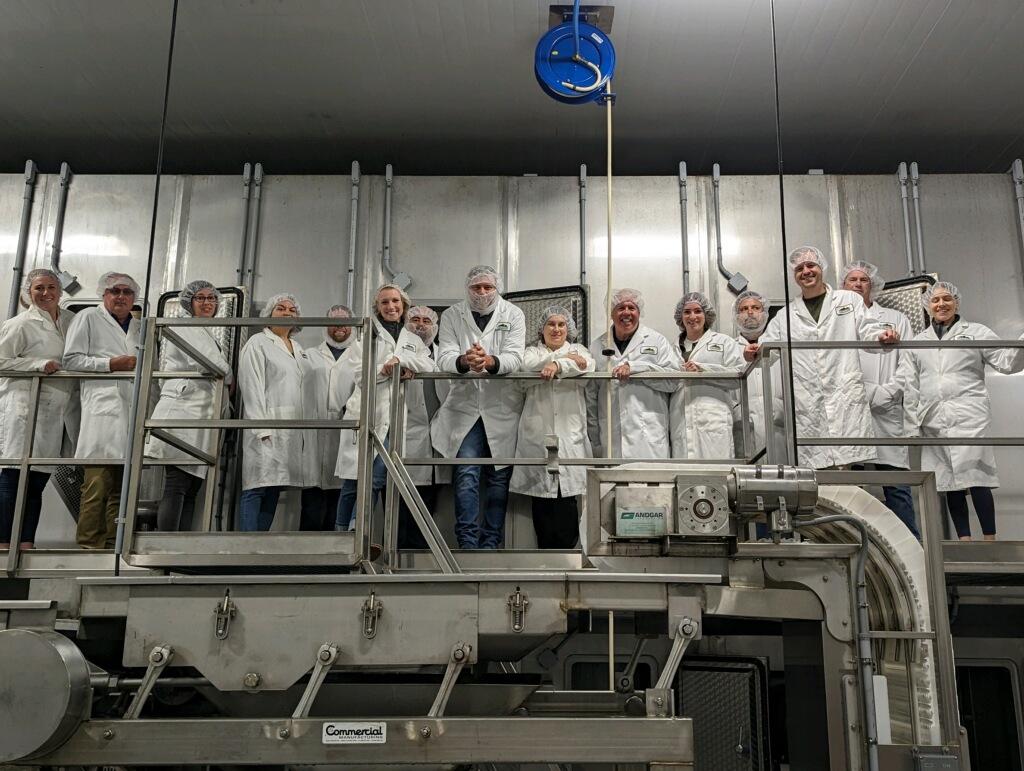 A group of people in white coats standing on a machine

Description automatically generated