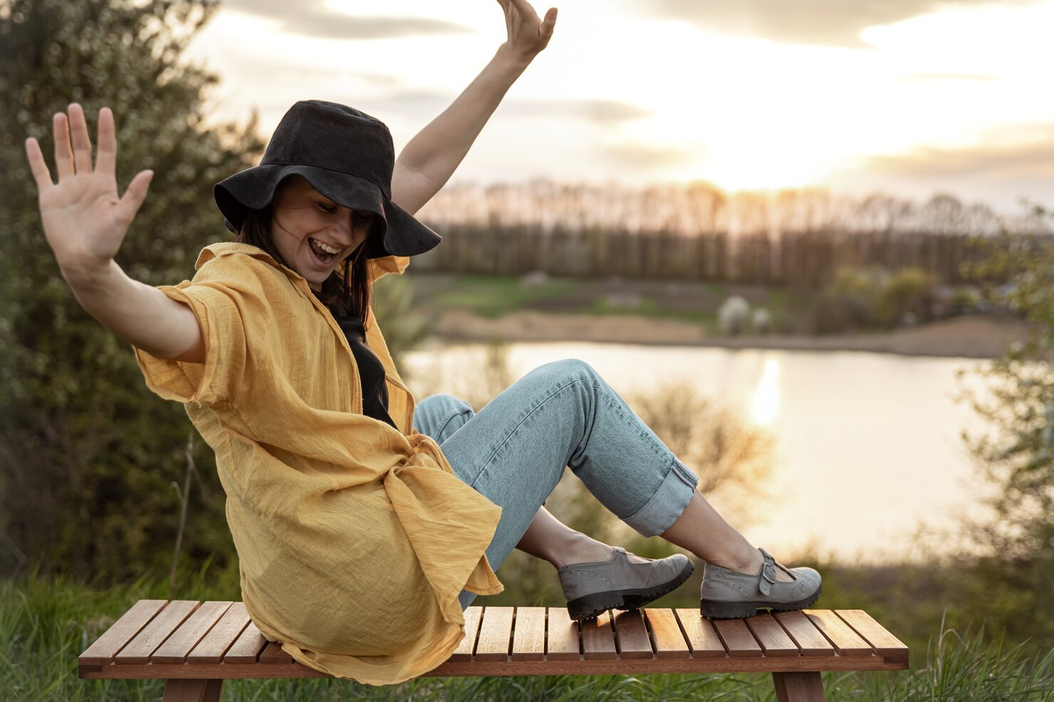 A woman enjoying life at sunset near a lake.