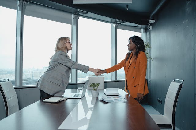 Two people shaking hands over a table.