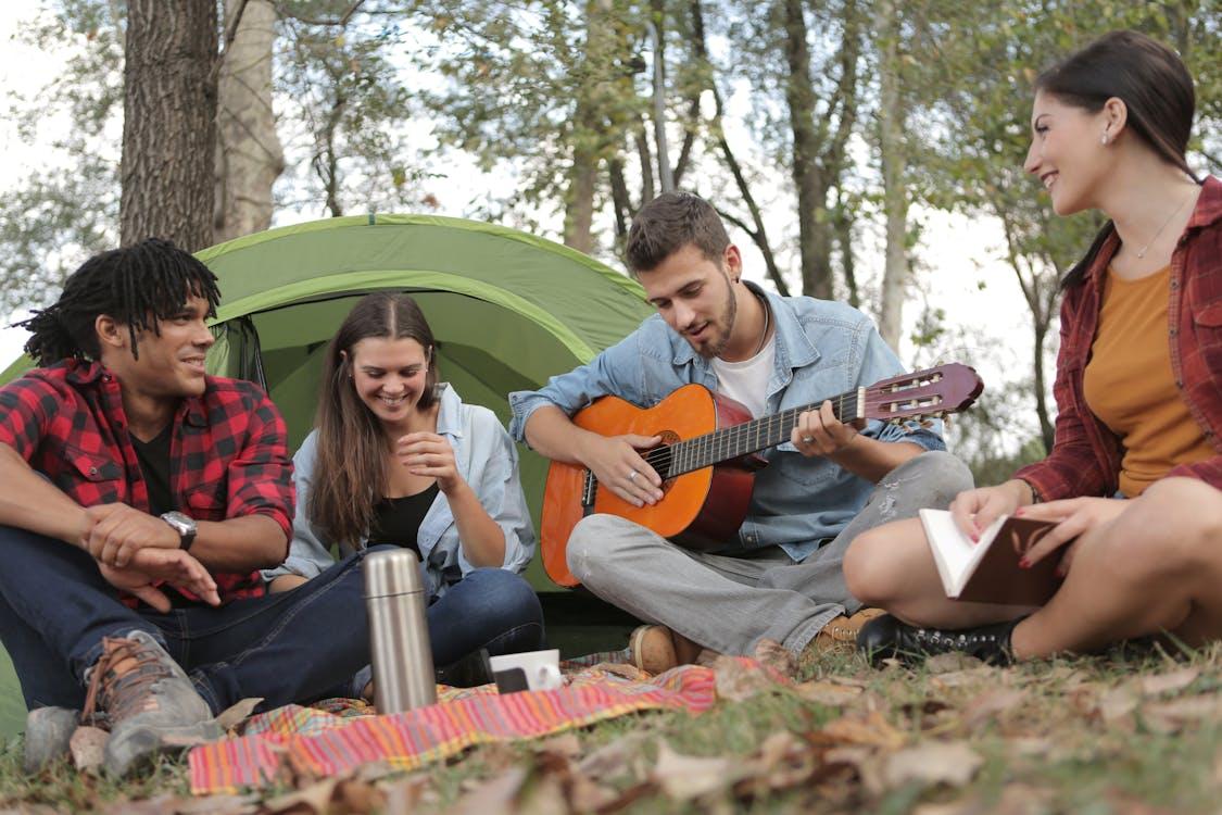 Free Acoustic Guitar Played By a Man Sitting On Grass Field  Stock Photo