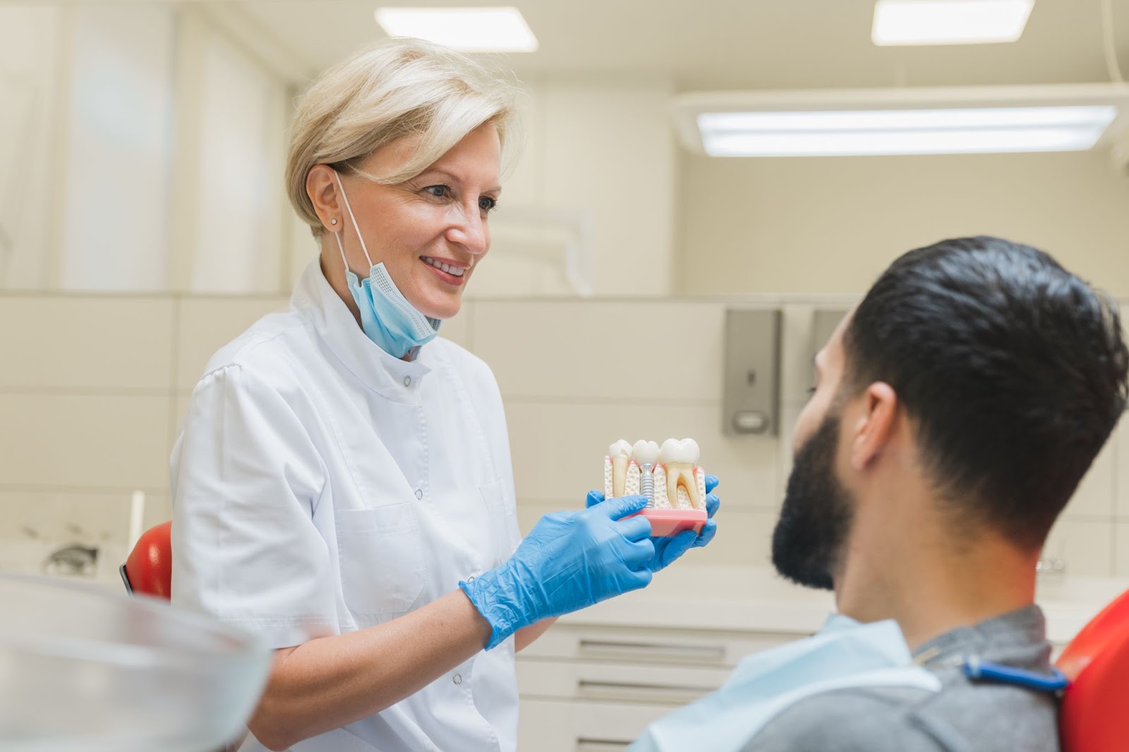 Dentist showing teeth implant procedure to patient