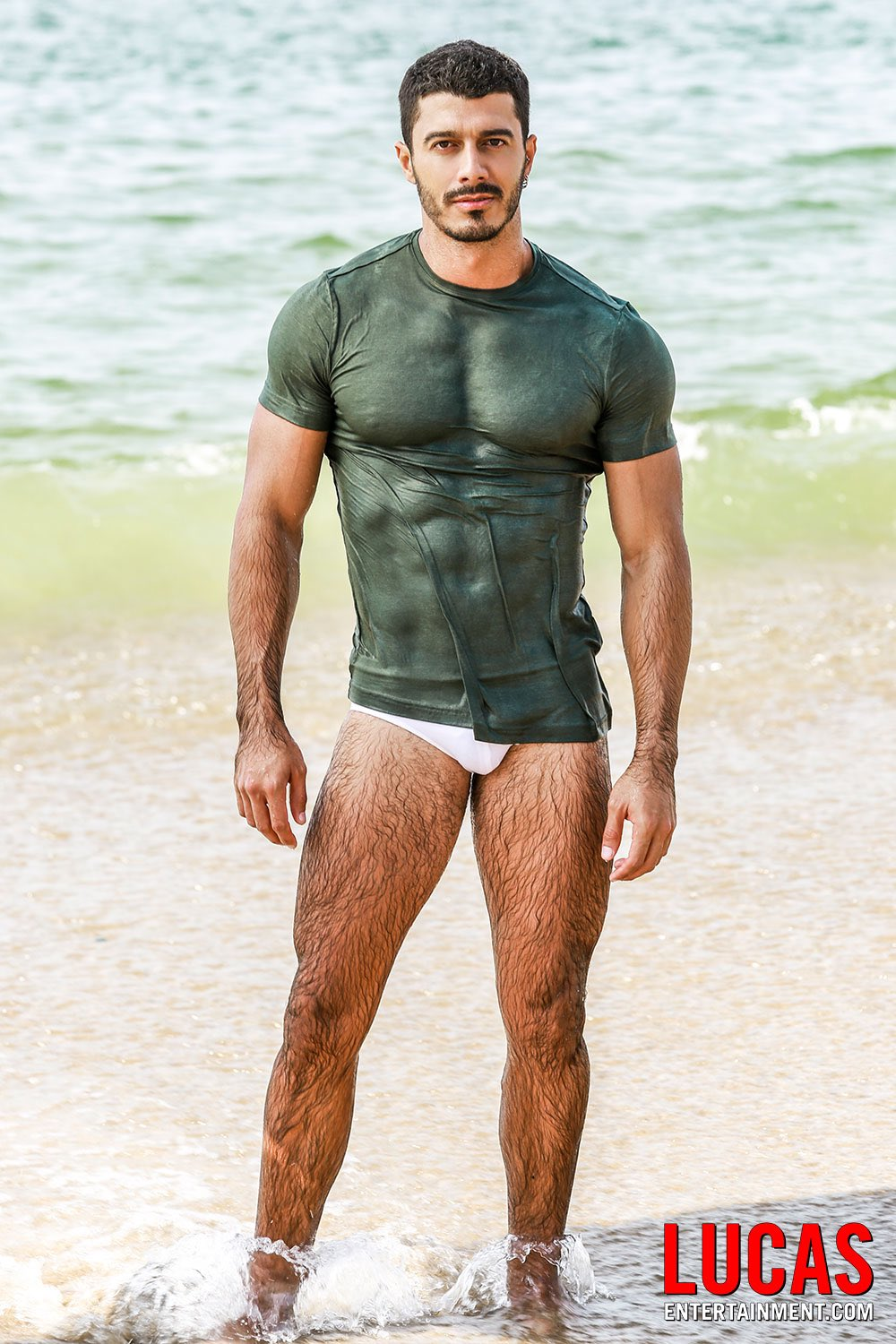 Lobo Carreira emerging from the ocean wearing a wet tight green t-shirt and white speedo for lucasentertainment.com promo shot