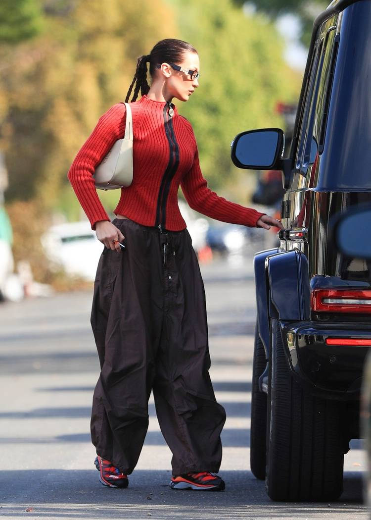 Bella Hadid wearing  a pair of parachute pants with Salomon sneakers; Versace sunglasses