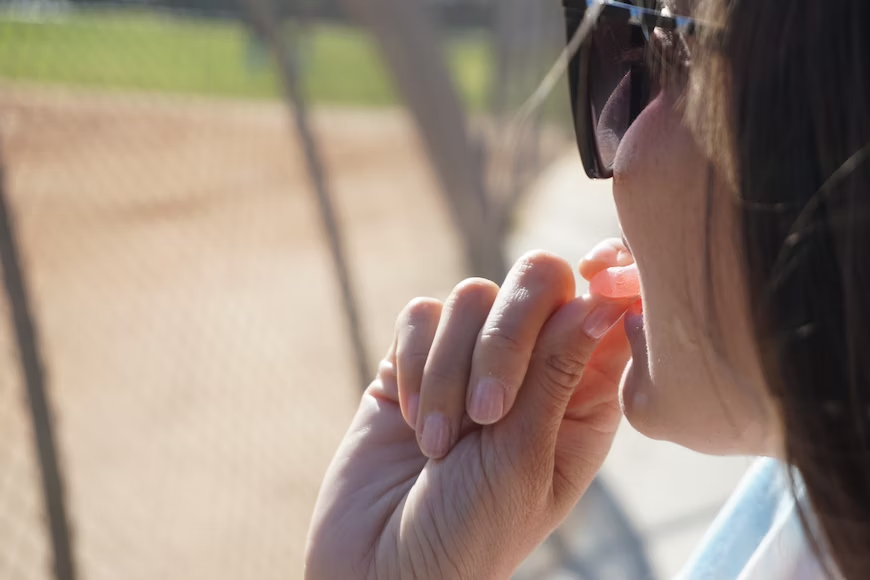 A woman putting a gummy in her mouth while outside