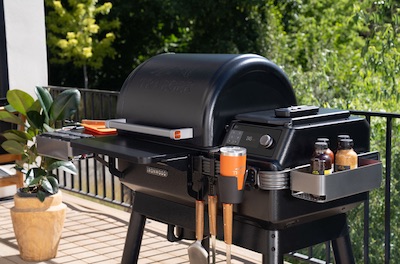 Traeger Ironwood pellet grill on a deck with greenery surrounding the area.