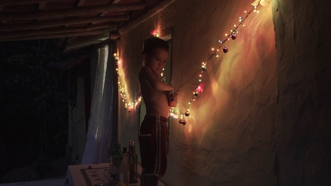 Samuel segurando luzes de Natal na parede