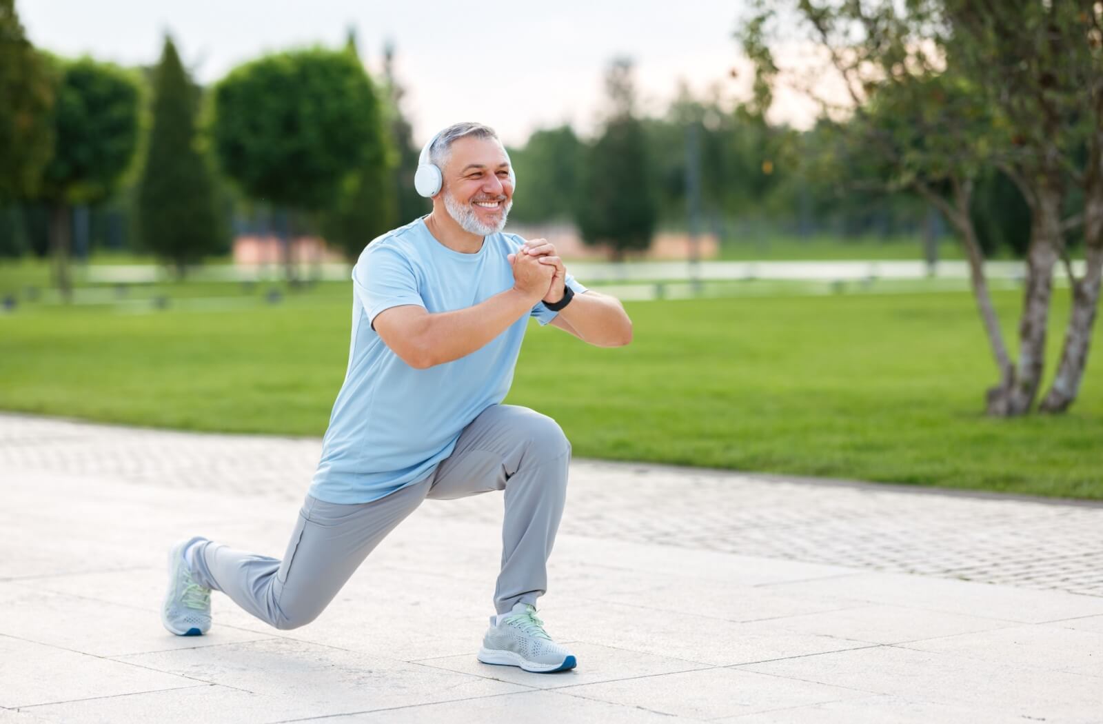 An older adult man warming up for his exercise in a park.