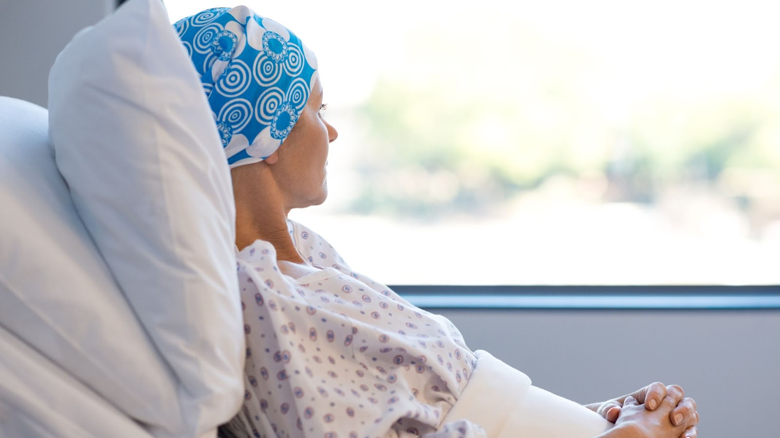 woman looking out window who is in the hospital with cancer