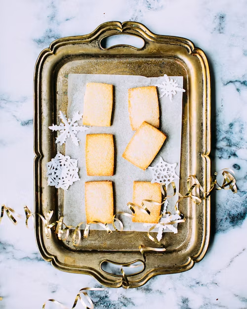 Shortbread holiday snacks on a silver platter and marble counter with snowflake cutouts