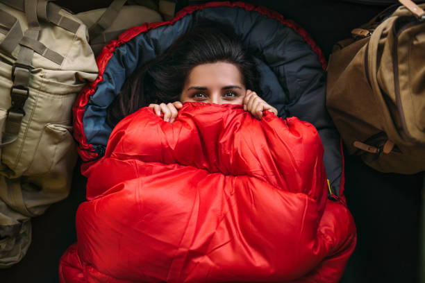 テントの中の快適な寝袋に身を着た若い女性、トップビュー。寝袋に入。寝袋に入寝袋に包まれた旅行者。旅行、キャンプコンセプト、冒険。テンラで悯ト