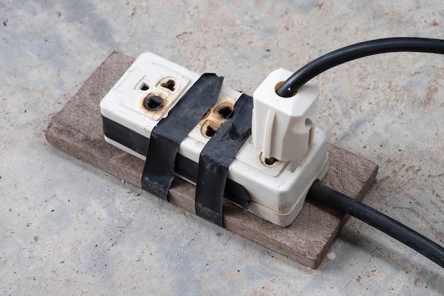 Photo burnt electrical socket and plug poor quality product on the cement floor background
