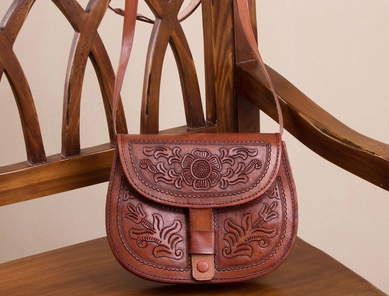 A brown leather purse on a chair

Description automatically generated