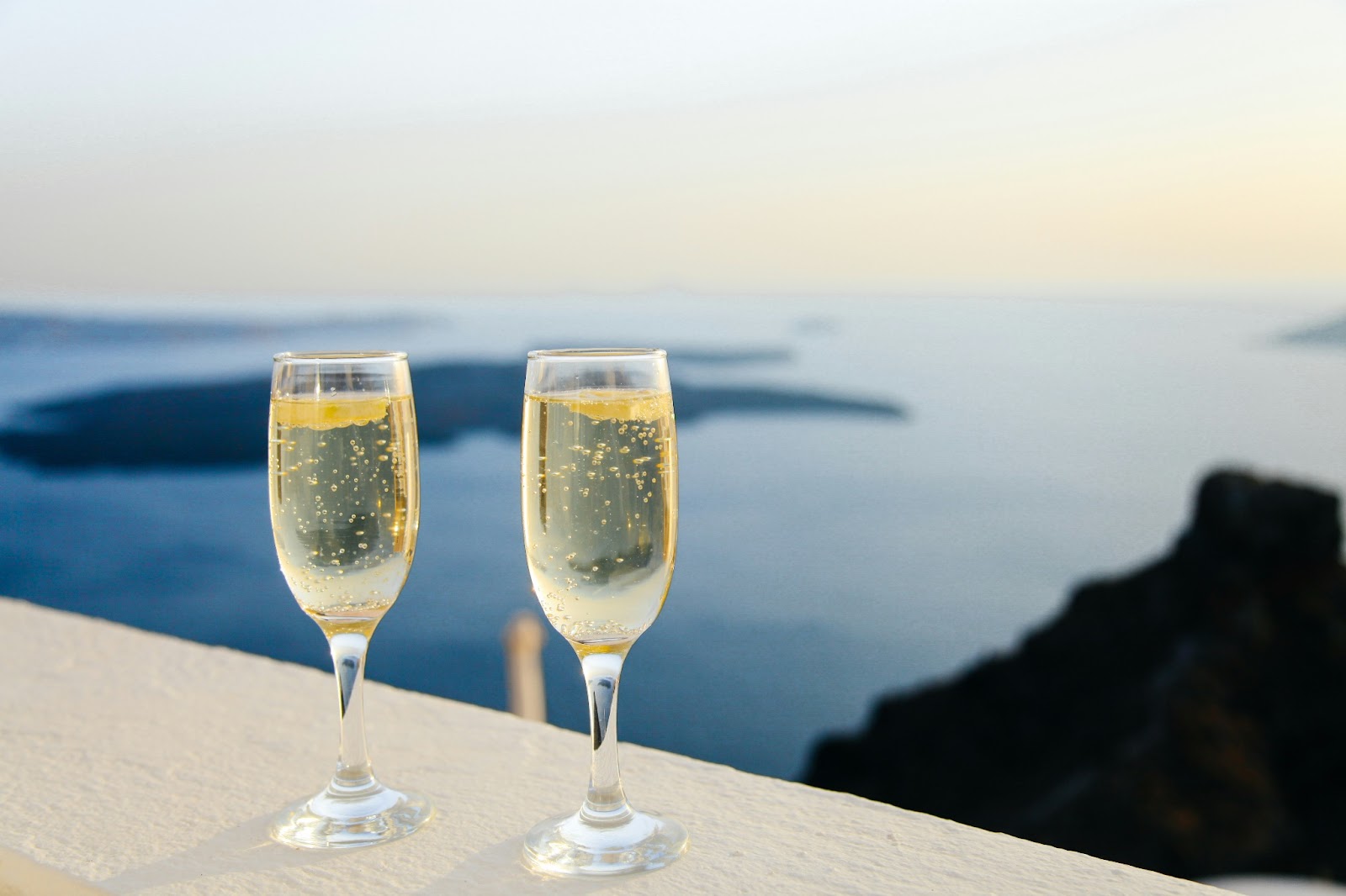 A couple enjoying a glass of champagne with clear blue waters in the background.