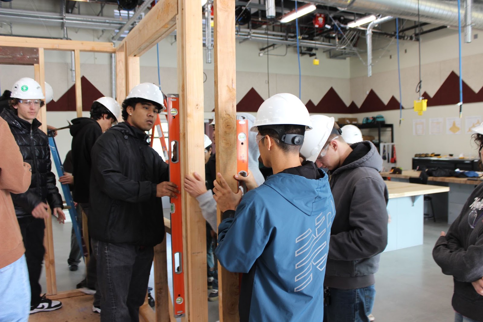 Students Inside Working with Wood, Measuring, and Wearing Hard Hats.