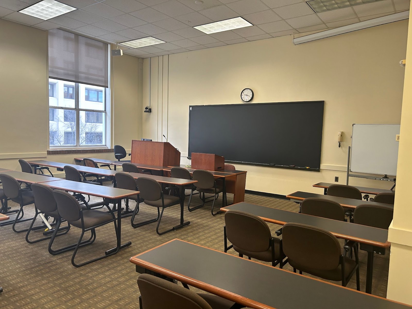 View of the front of the room: Room camera, lectern, hotline phone, projector screen.