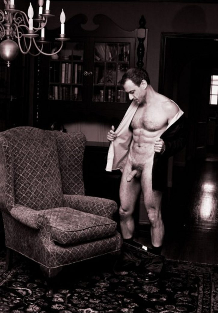 young David Pevsner stripping off his robe to reveal his naked body in antique looking study near big arm chair