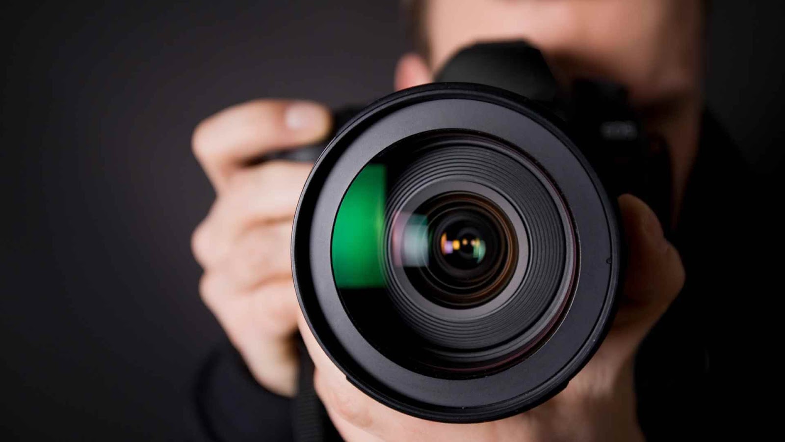 LinkedIn Photo - A person holding a camera with a large lens, focusing on the viewer.