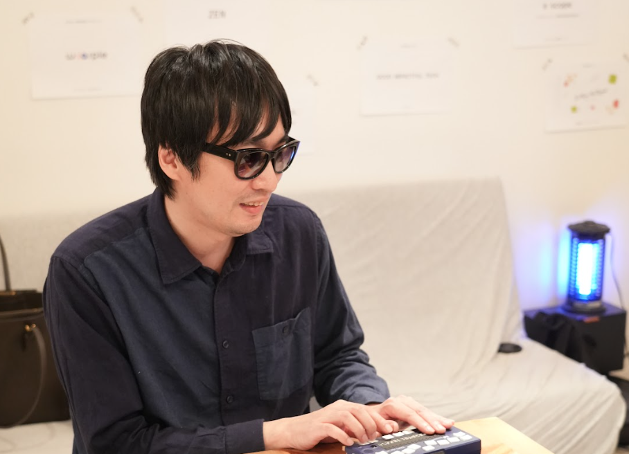 視覚障害リードユーザーの白井さんが、点字ディスプレイを入力している。