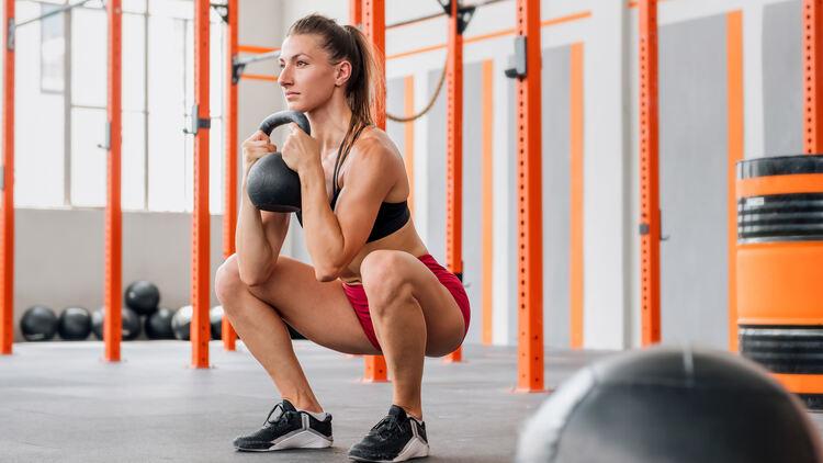 A person squatting with a kettlebell

Description automatically generated