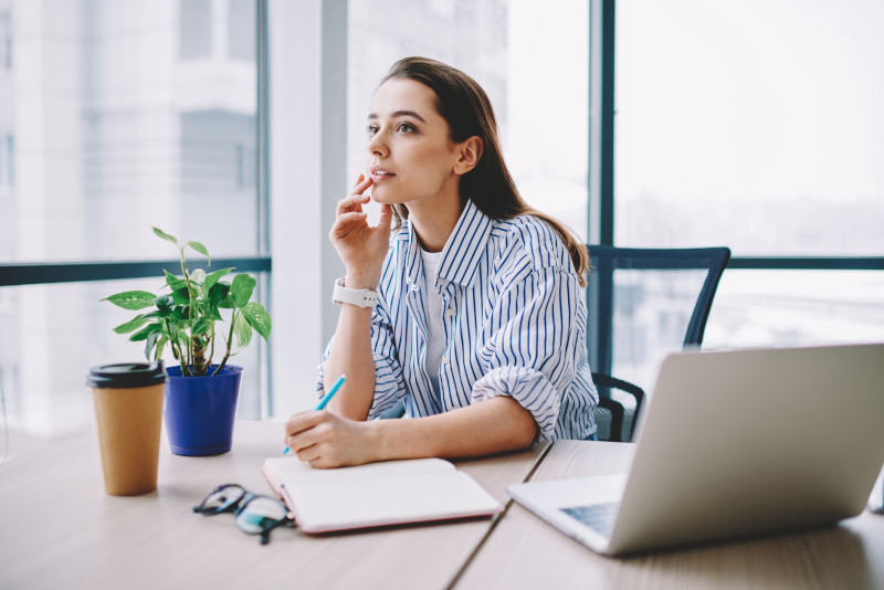 Mujer reflexiva escribiendo 