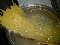 Spaghetti diletakkan ke dalam periuk air mendidih untuk memasak