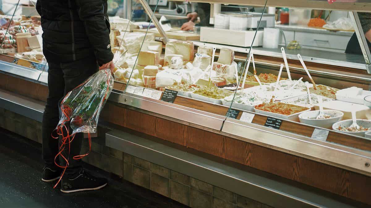 man with bouquet of roses standing in front of food display