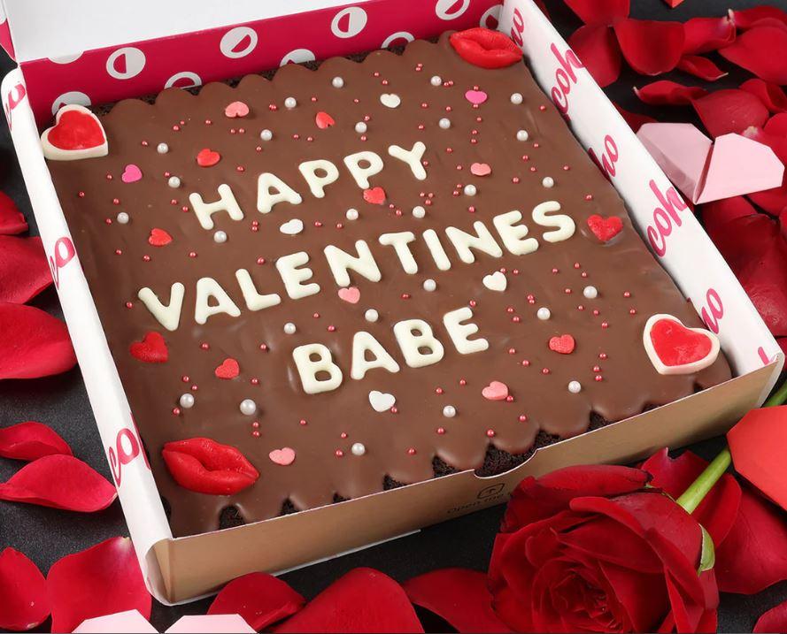 A chocolate cake with white letters and red hearts

Description automatically generated