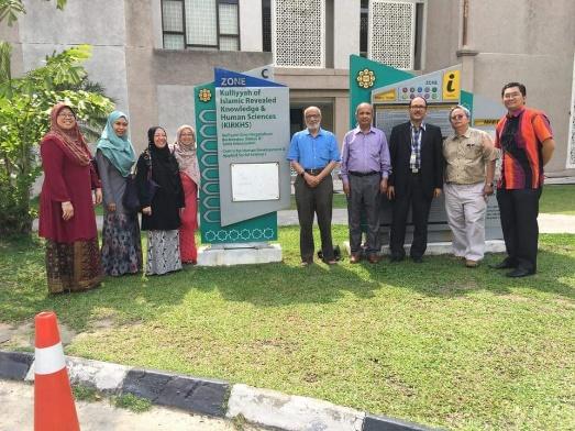 A group of people standing in front of a sign

Description automatically generated