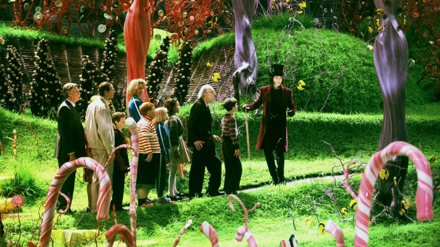 Charlie leads the group on a captivating tour through the whimsical and vibrant grounds of Willy Wonka's chocolate factory, reminiscent of the enchanting and magical essence found in the best comfort Christmas films. His face lights up with wonder as he showcases the magical and fantastical elements to his wide-eyed companions.