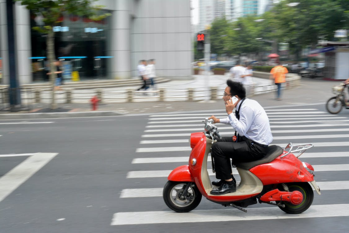 an office worker talking on the phone while riding a moped