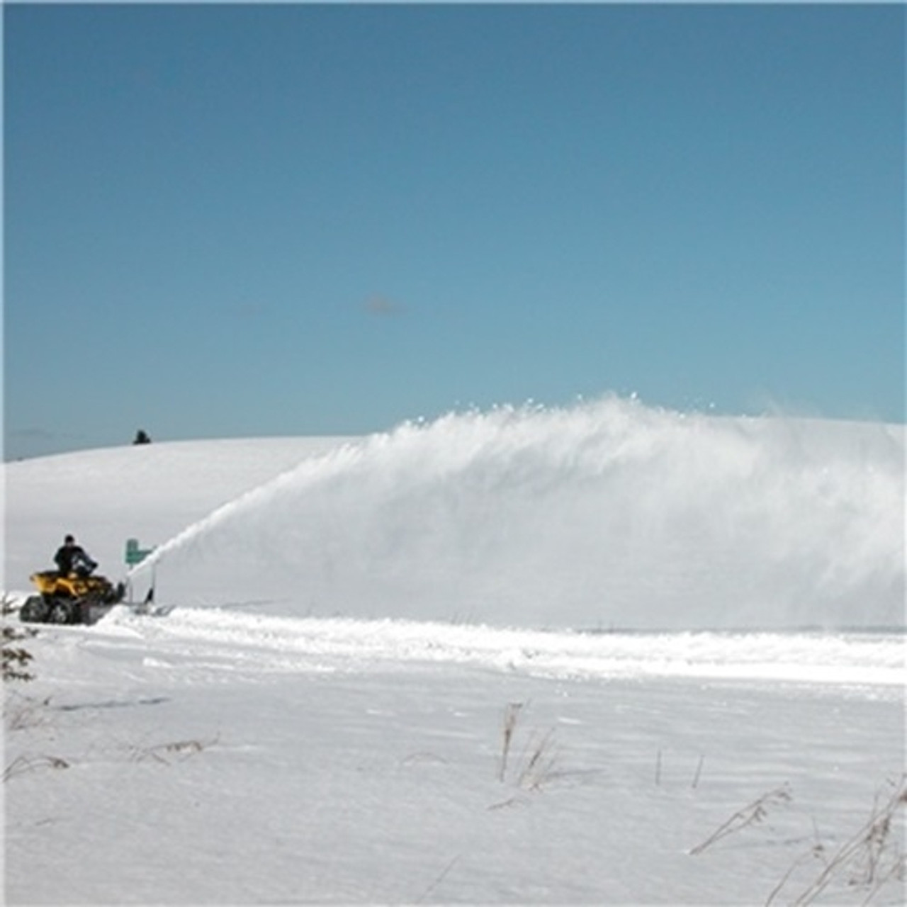 A side-angle shot of a Polaris General Snowblower by Bercomac, installed on an ATV and in use on snowy terrain