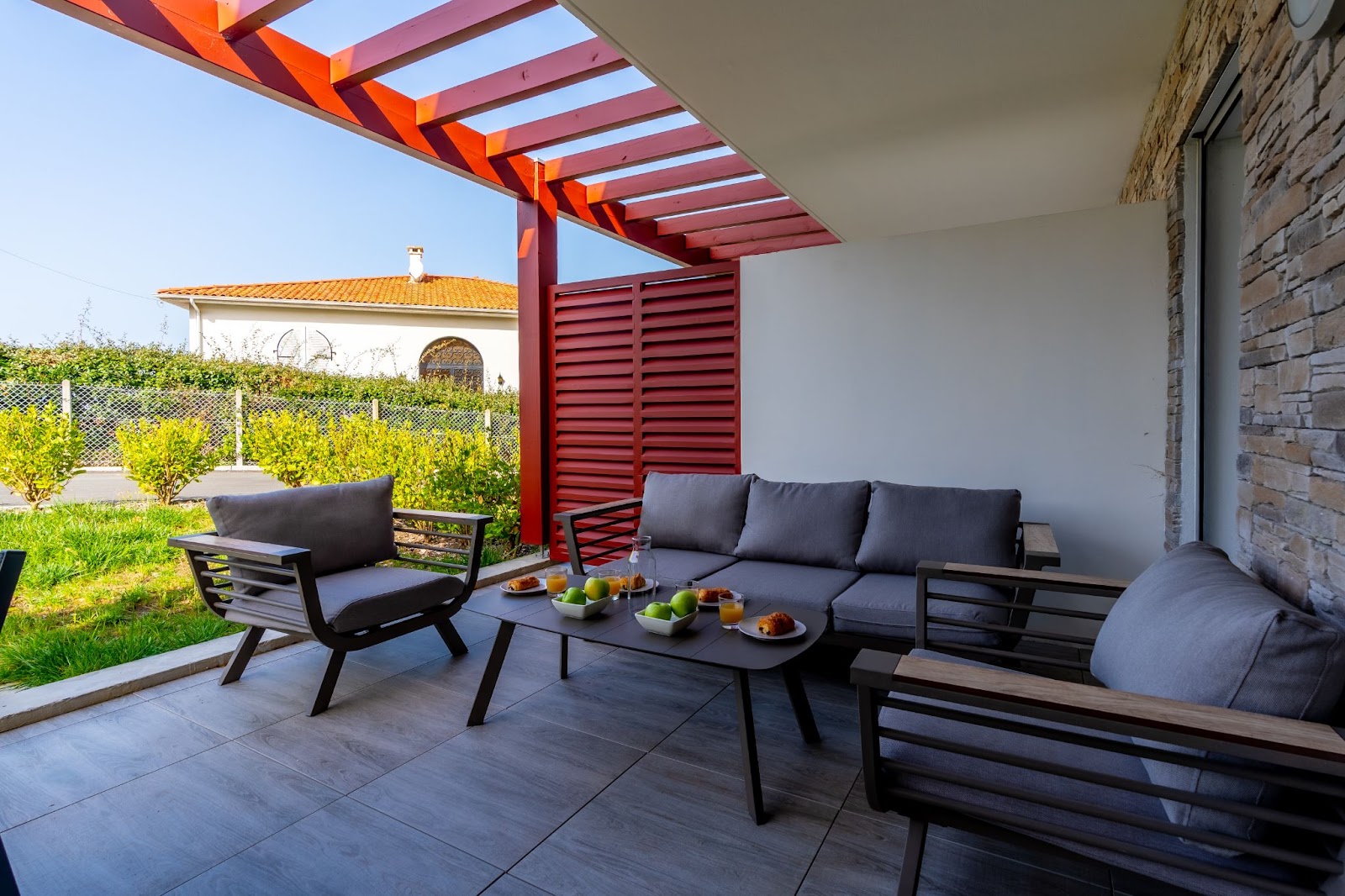  An outdoor wooden deck with chairs and a coffee table with fruit on top.