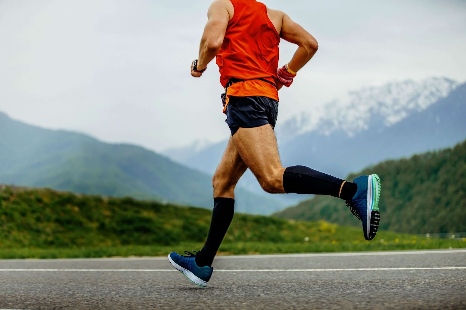A man wearing compression socks while running outdoors.