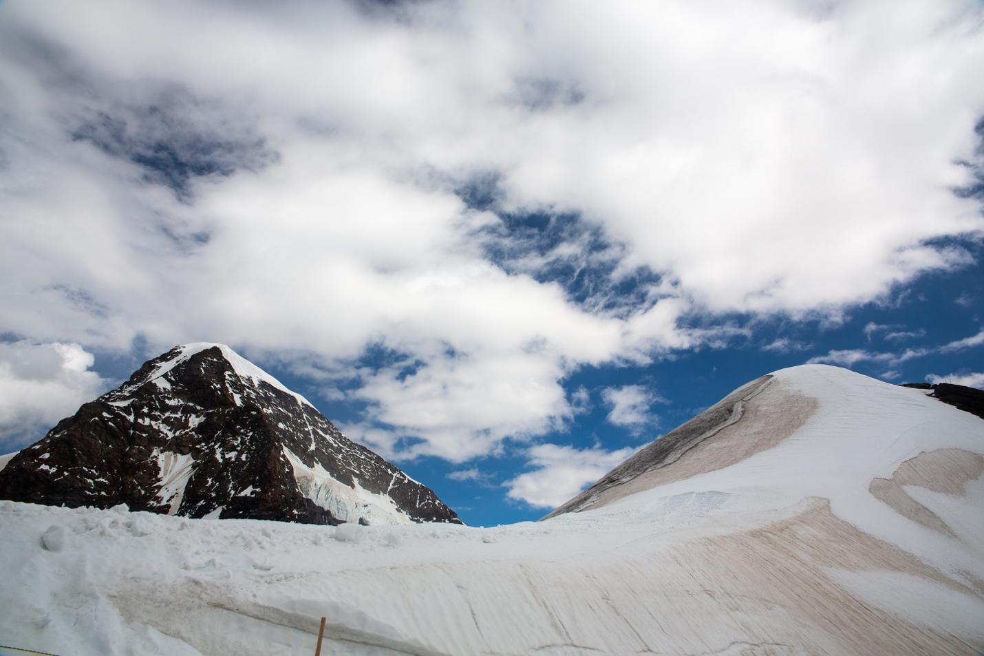 A snowy mountain with blue sky and clouds

Description automatically generated