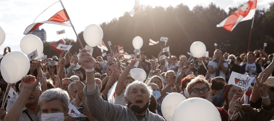 A group of people holding white balloons Description automatically generated