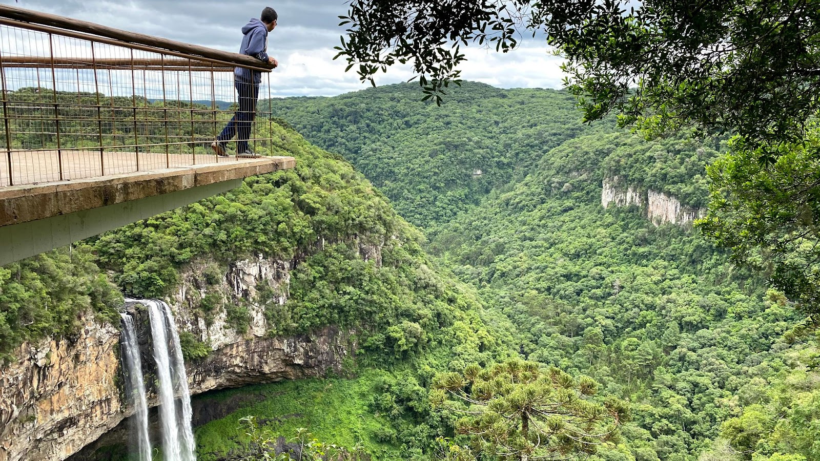 Pessoa no mirante do Parque do Caracol, observando a Cascata do Caracol abaixo e toda a vegetação do parque que se estende pela imagem.