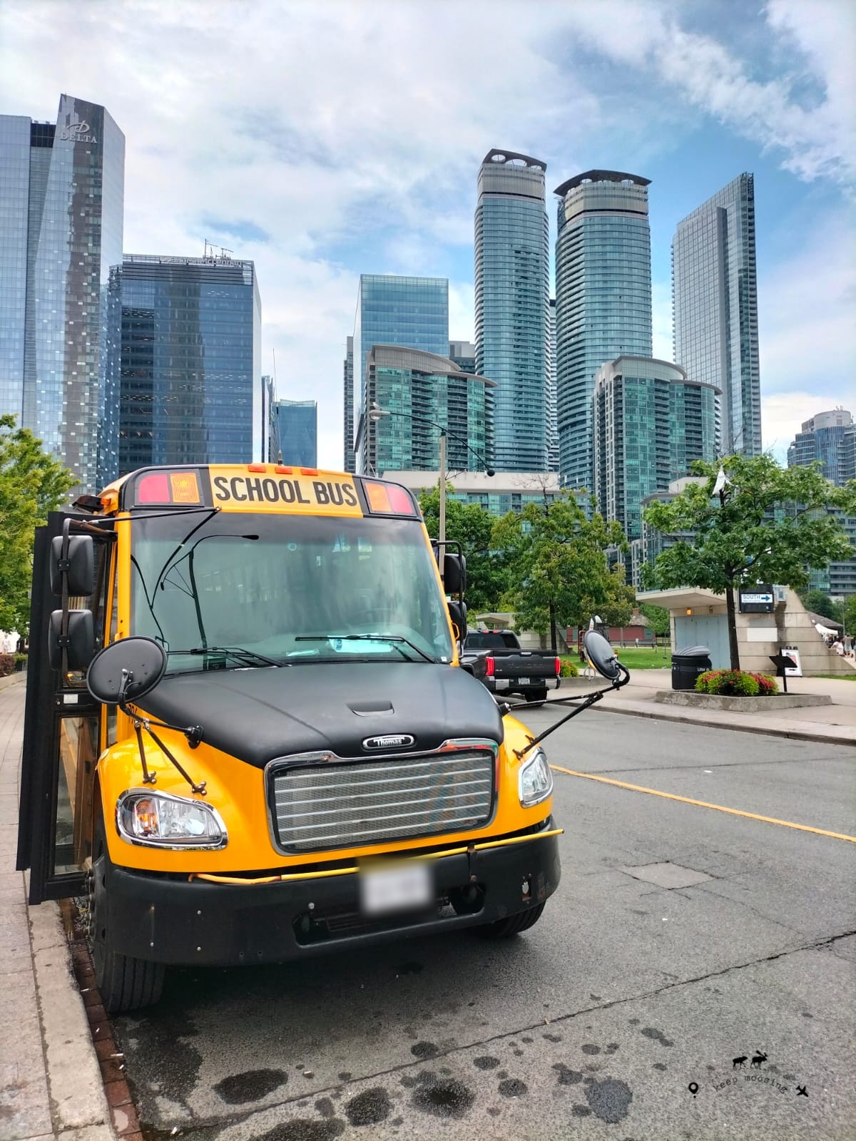 What to see in Toronto and Niagara Falls. A yellow-black school bus in the foreground with Toronto skyscrapers in the background.