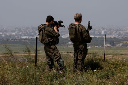 Due soldati israeliani armati si trovano sul lato israeliano del confine tra Israele e Gaza e guardano il territorio palestinese